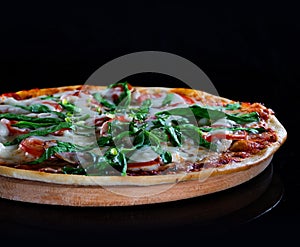 Italian hot pizza with tomato, spinach and pieces of bÐ°Ñon isolated on black background